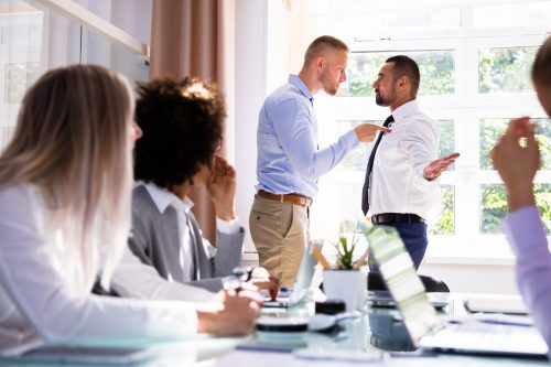 Picture of office setting one male employee bullying harassing another male employee